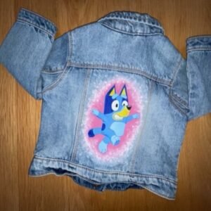 Back of child's denim jacket showing Bluey dancing on a pink background